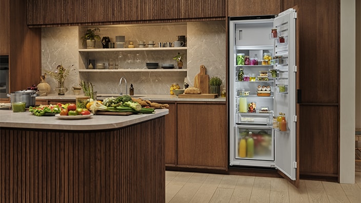 A hand is opening a drawer in a fridge-freezer.