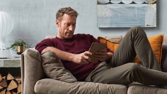 Un homme confortablement assis sur un sofa utilise l’application.