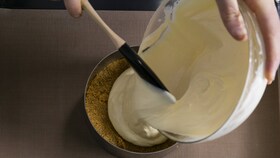 Un boulanger-pâtissier versant le mélange lisse du gâteau au fromage dans un cercle à gâteau prêt à enfourner