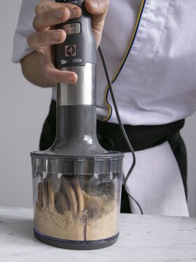 Un boulanger-pâtissier versant le mélange lisse du gâteau au fromage dans un cercle à gâteau prêt à enfourner