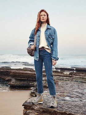 Une femme en jean debout sur un rocher
