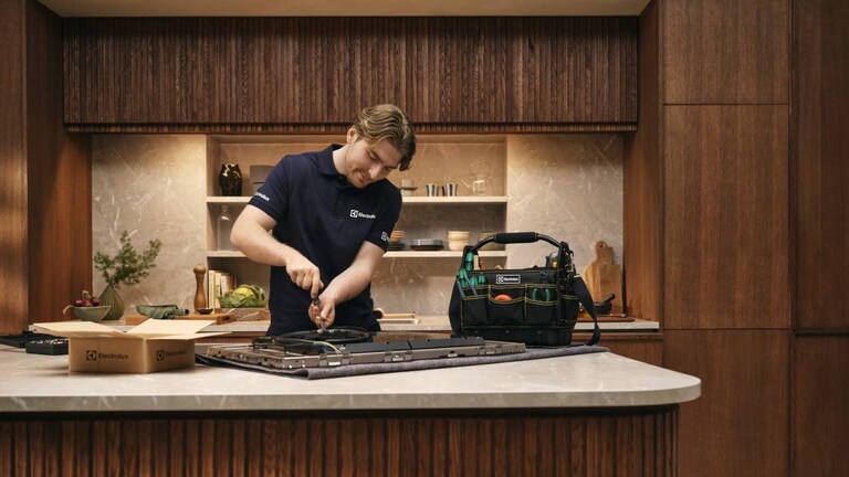 Technicien de maintenance réparant une plaque de cuisson dans une cuisine