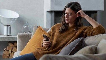 Femme assise sur un canapé avec un téléphone