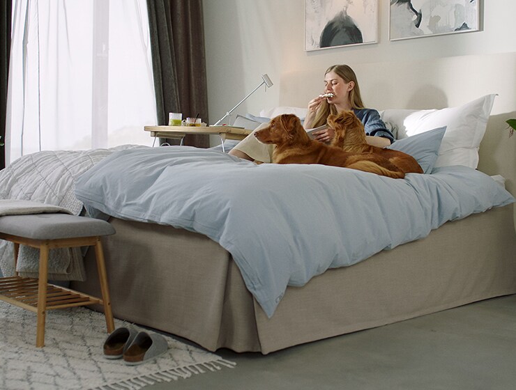Une femme et deux chiens assis sur un lit.
